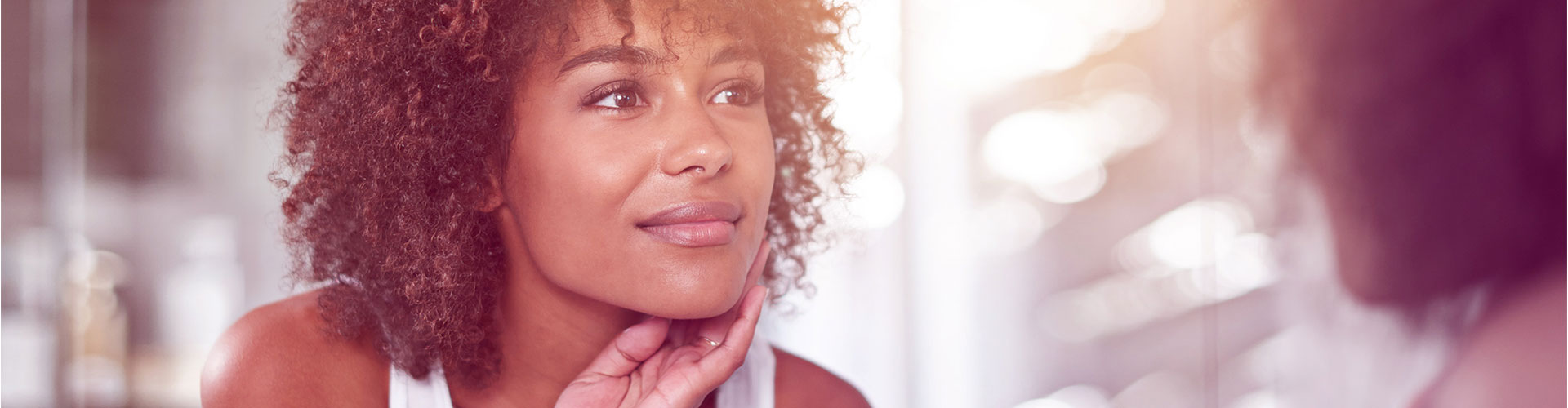 Blog banner featuring closeup of young black woman touching her face in the mirror