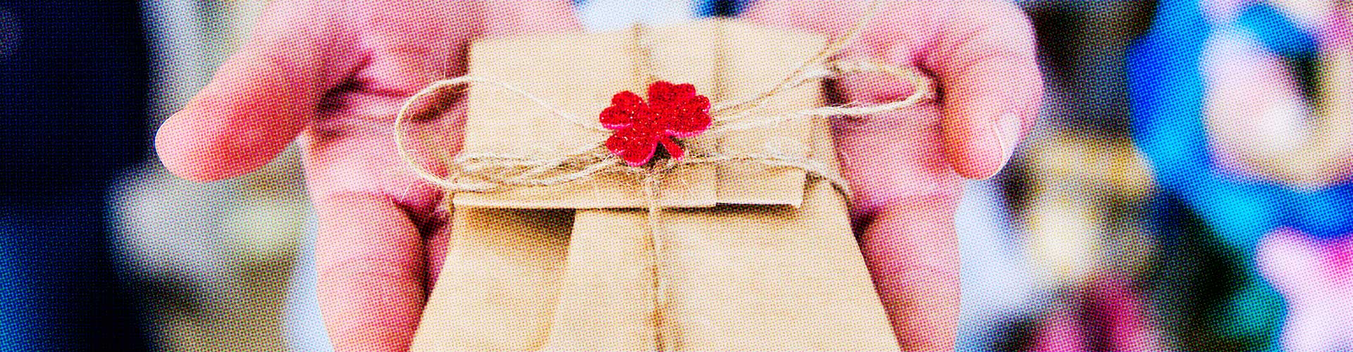Holiday Shopper Talk: Stockings to be Half Full blog banner featuring hands holding out a small brown paper wrapped gift