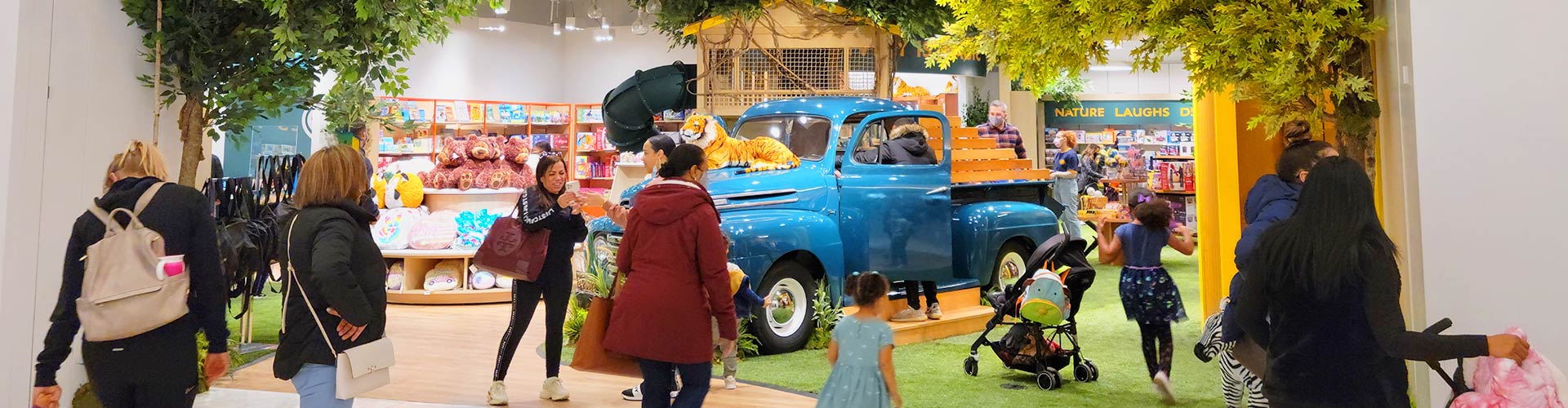 Adults and their kids exploring colorful, interactive store exhibit banner