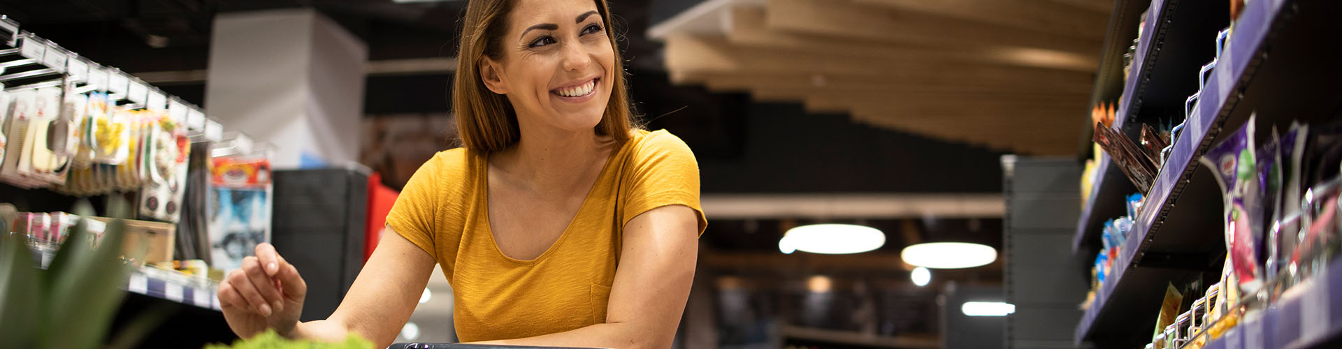 Banner featuring happy woman shopping in grocery aisle
