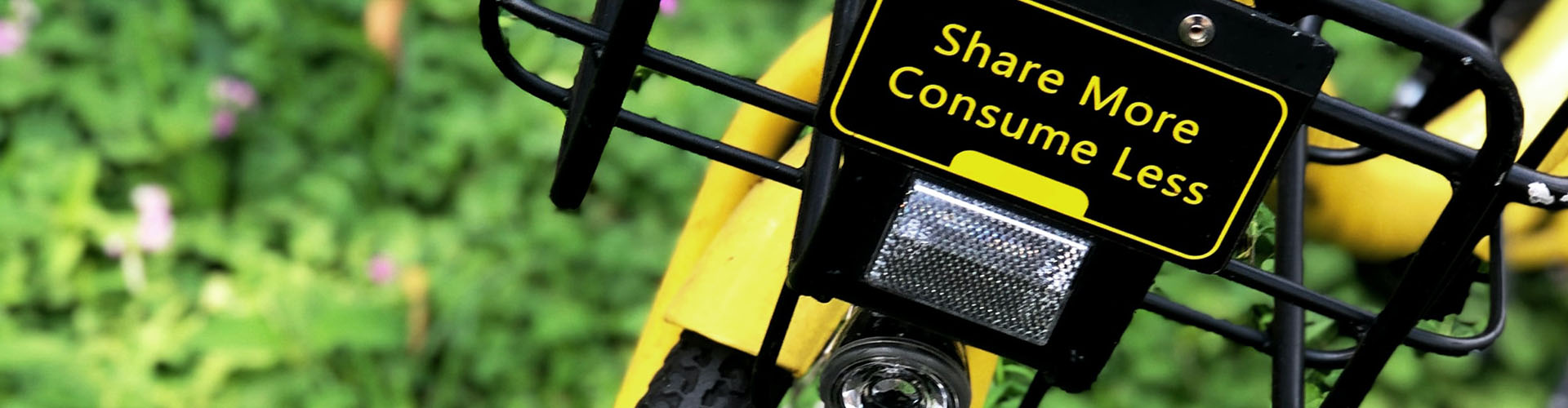Banner featuring bike with sign that says share more consume less